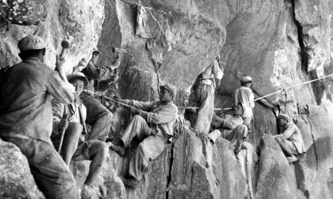 1954年，修筑康藏公路的解放軍戰(zhàn)士們在怒江兩岸的懸崖陡壁上辟山筑路。新華社稿 李萬春、張加里攝